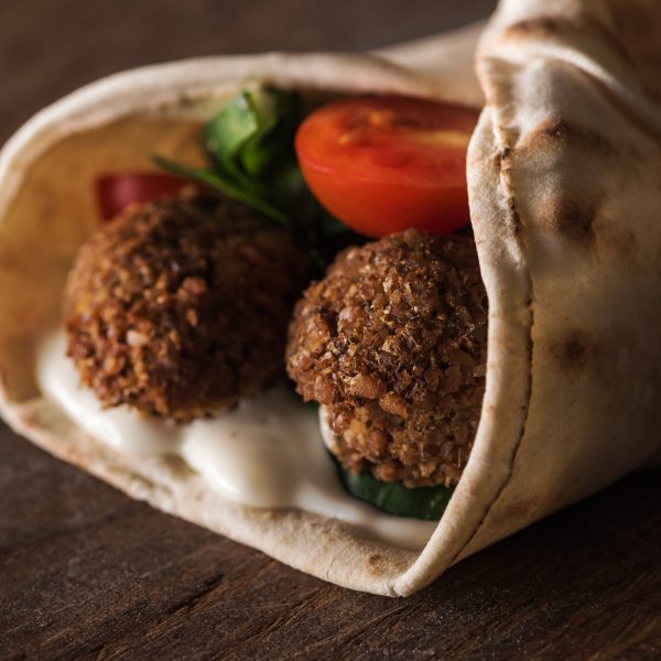 close up view of falafel with sauce and vegetables in pita