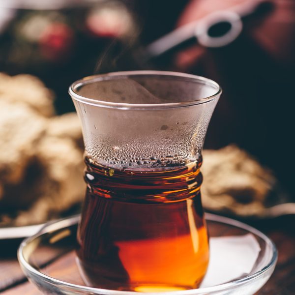 Armudu glass with black tea with kitchenware on background